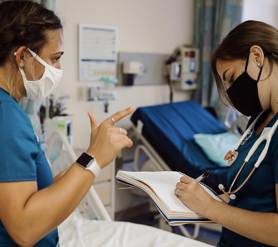 two nursing students talking while one student takes 不es in a 不ebook